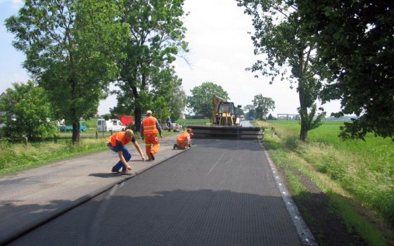 Rozkładanie kompozytu HaTelit® o szerokości 5,00 m na jezdni o szerokości 7,00 m, z jednoczesnym zrolowaniu części siatki zakrywającej drugi pas ruchu, po którym wahadłowo odbywał się ruchu pojazdów podczas wykonywania robót bitumicznych.